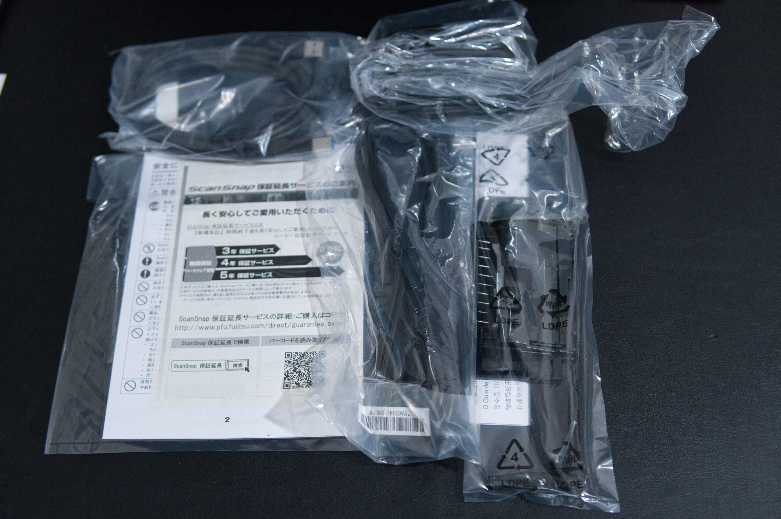 ScanSnap iX1600 の同梱品一式（ケーブル類・保証書が袋に入った状態）