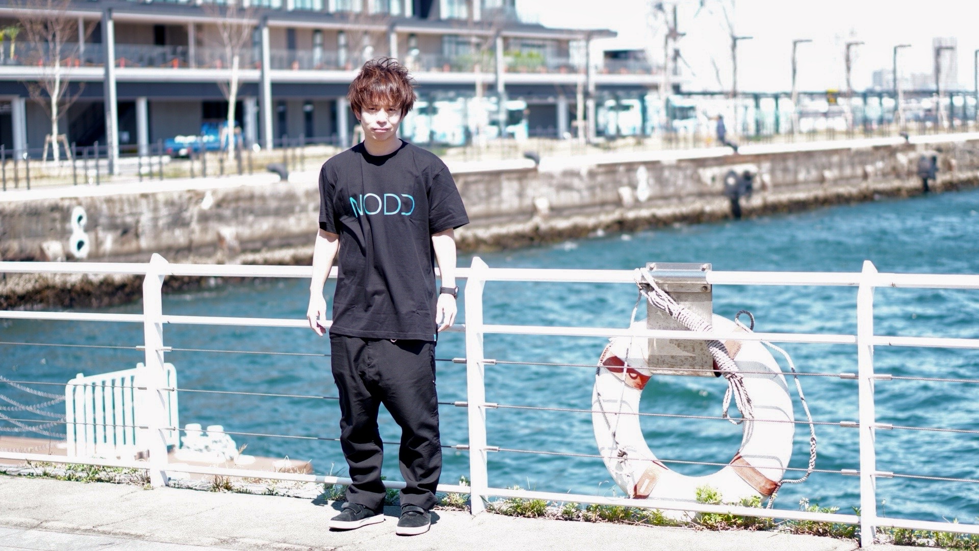 NODDのTシャツで横浜の海沿いに立つ石田