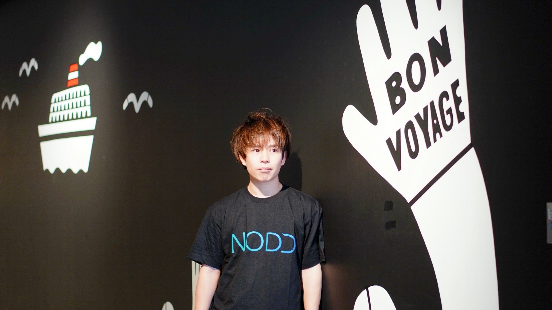 NODDのTシャツで氷川丸モチーフの壁画と並んで立つ石田